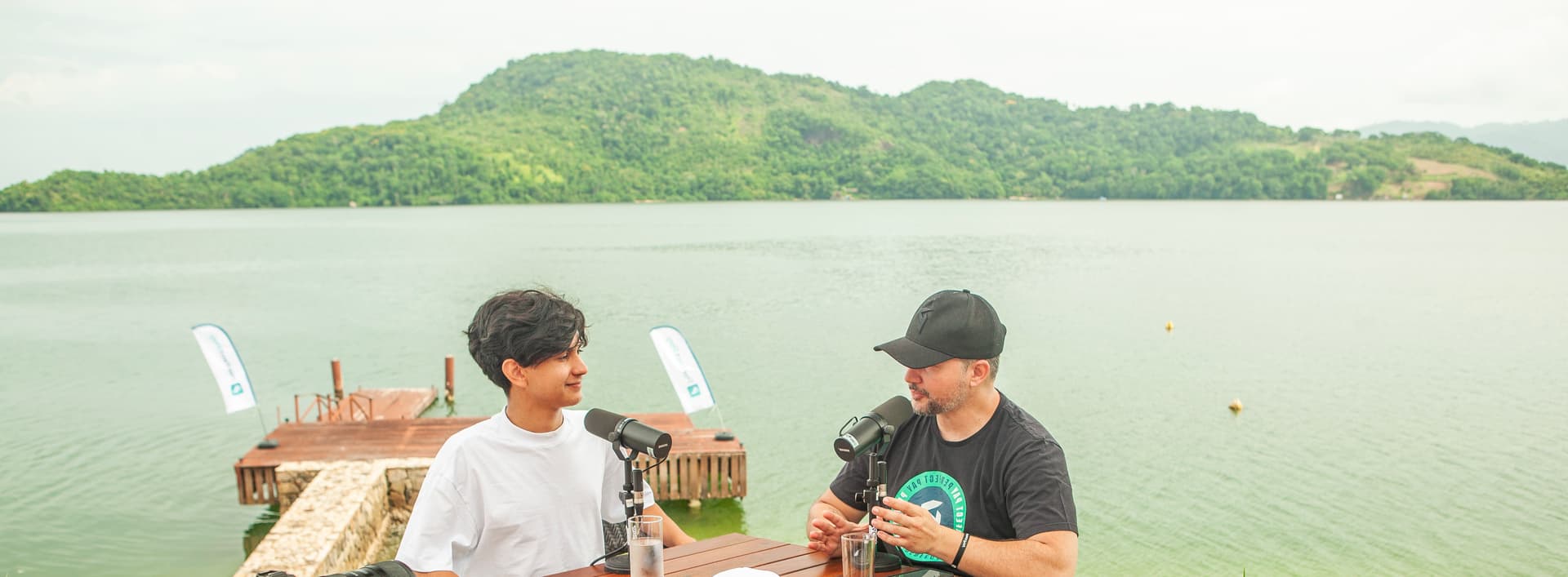 Arthur Oliveira gravando podcast ao ar livre com vista para lago e montanhas